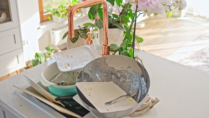 Kitchen Sink Full of Dirty Dishes Plate Drinking Glass Cutlery and Cutting Board