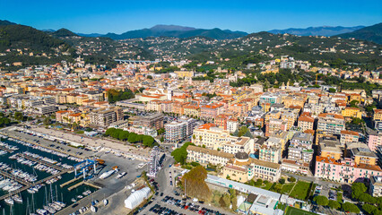 Fototapeta premium Chiavari, a charming coastal town in Italy's Liguria region, viewed from the air showcases its scenic waterfront, vibrant marina, and historic architecture nestled between the green hills