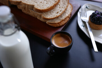 Hand holding a black cup of hot espresso coffee mugs and a cup of espresso coffee with black table in isolate black background