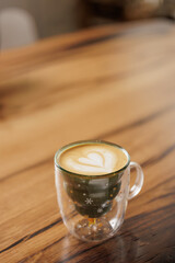 A Christmas mug with green and gold star motifs is filled with coffee with a heart drawing. Concept of enjoying a specialty coffee in a coffee shop.