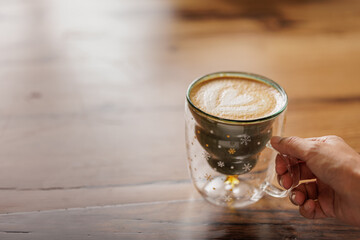Hands of unrecognizable woman in red sweater sitting at table enjoying specialty coffee in cafe...