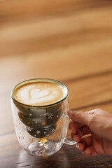 Hands of unrecognizable woman in red sweater sitting at table enjoying specialty coffee in cafe with Christmas mug with star drawings.