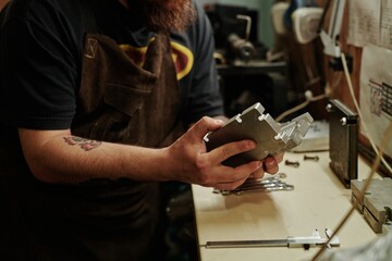 Hands of unrecognizable male worker of plastic recycling factory opening press mold with new metal detail in workshop
