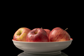 Several red apples in a ceramic dish, macro, isolated on a black background.