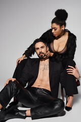 A couple shares a tender and alluring moment, showcasing their close bond and fashion sense.