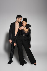 A couple radiates love and style, showcasing their fashionable outfit choices in a playful moment.