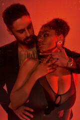 A loving couple shares an intimate moment, enveloped in warm red tones and vibrant energy.