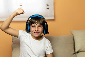 Portrait of a boy with headphones and raised arm. Concept of victory celebration in an online video game