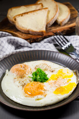 Fried eggs and bread for breakfast on a gray background.