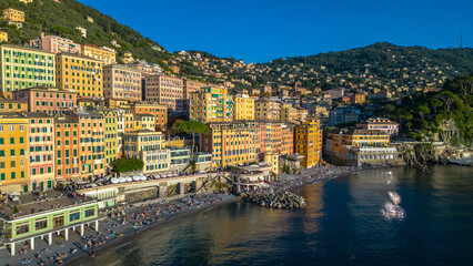 Camogli, a charming fishing village on Italy's Ligurian coast, captured from the air at sunset, reveals its colorful houses and historic harbor bathed in a warm, golden light