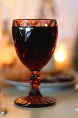 Various Christmas decorations, cookies, chocolate, nuts and tangerines, wine glasses and lit candles on the table. Holiday hygge at home. Selective focus.