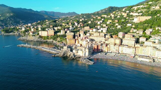 Camogli, a charming fishing village on Italy's Ligurian coast, captured from the air at sunset, reveals its colorful houses and historic harbor bathed in a warm, golden light