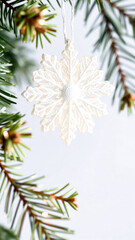 delicate white snowflake ornament hanging on an evergreen branch