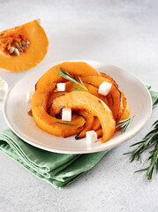 Roasted pumpkin slices with garlic, rosemary and feta cheese. Vegetarian food.