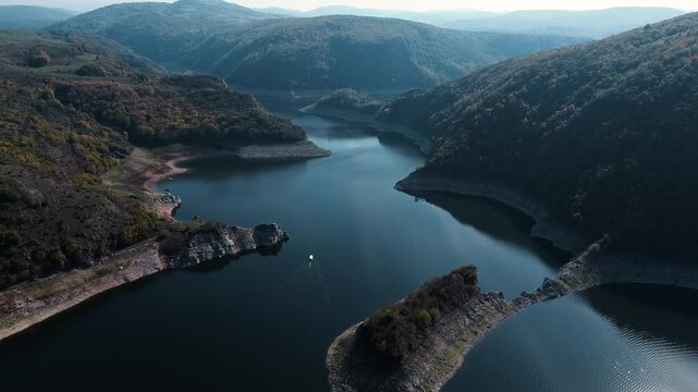 Aerial drone view of the canyon of the river Uvac in southwestern Serbia. A winding river with clear blue water on sunny autumn day. Yellow-green mixed forest from a bird's-eye view