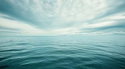 Fototapeta premium A serene view of calm ocean waters under a cloudy sky, evoking tranquility and reflection.