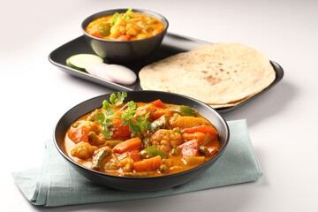 Mix vegetable curry - Indian main course recipe contains Carrots, cauliflower, green peas and beans and served in ceramic ware with Chapati ,Indian flat bread , roti