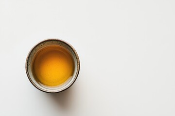 A small ceramic cup featuring Japanese whiskey sake and tea on a white backdrop with space for text Embracing Japanese aesthetics and wabi sabi