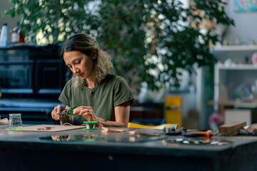 in a large green workshop on a woman with green hair creates decorative flowers working with metal tape decor on the mirror handicrafts