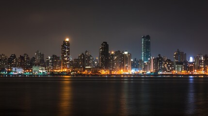 Nighttime city skyline illuminated by light reflecting on water.