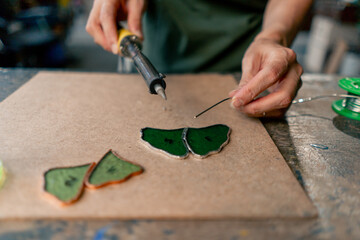 in a large green workshop on a woman with green hair creates decorative flowers working with metal tape decor on the mirror handicrafts