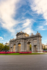 Fototapeta premium Alcala Gate with a sky full of clouds at dawn, photo with copyspace, Madrid, Spain.
