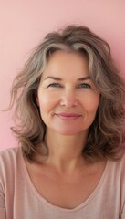 Fototapeta premium Middle-Aged Woman's Warm Smile Against Pastel Pink Monochrome Background