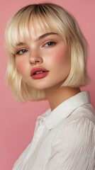 Young woman with short blonde hair poses against a pink backdrop