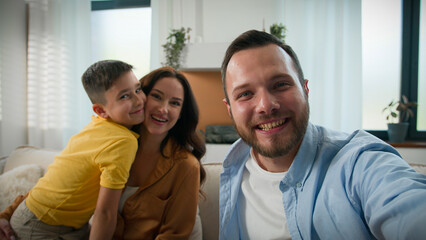Obraz premium Happy Caucasian family talking on online video call wave hello greeting looking at webcam father mother son bloggers recording vlog parents kid boy child communicate together remote on device at home