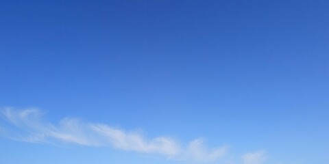 A tranquil blue sky with a few wispy stratus clouds stretching across the horizon, calming, nature, serene