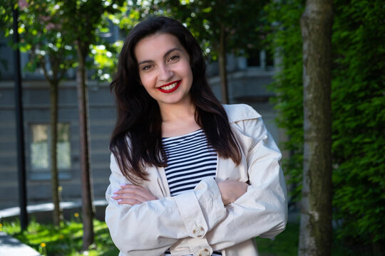 a girl with red lips smiles with her arms crossed