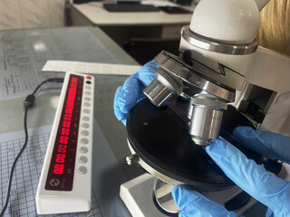 Laboratory technician looks at a blood sample through a microscope, equipment and scientific experiments in the laboratory, research and analysis of the sample, global pandemic