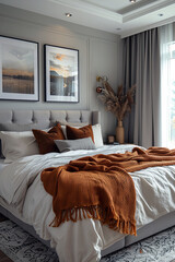A stylish bedroom with a gray palette, accented by burnt orange throws and pillows, featuring modern artwork, soft lighting, and a cozy, inviting atmosphere.