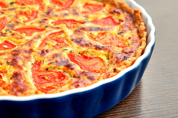 Delicious homemade quiche with fresh tomato slices and melted cheese, baked to perfection in a ceramic dish. A perfect savory pie for breakfast, brunch, or dinner.