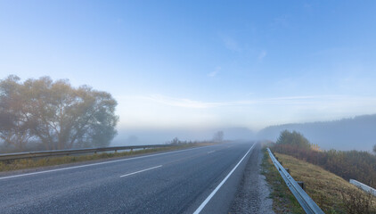 A foggy morning on a road with a tree in the background