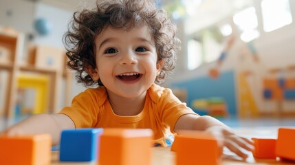 A joyful child with curly hair excitedly plays with vibrant blocks, showcasing a moment of pure delight and curiosity in a well-lit, inviting indoor play area.