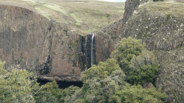 Waterfall off a cliff with green grass in slow motion 