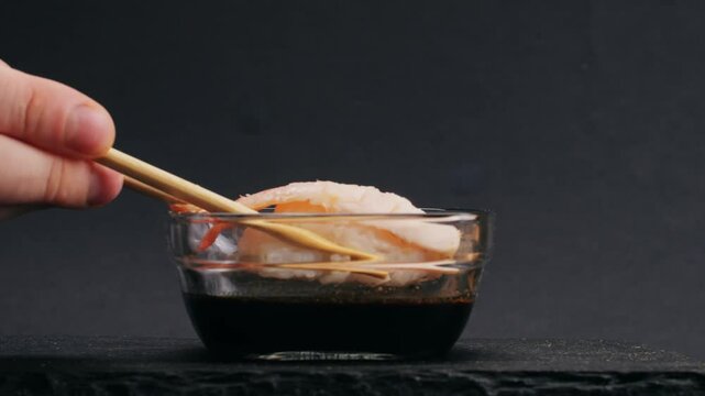 Shrimp sushi or Japanese ebi sushi set on black plate with wasabi in flash lighting.