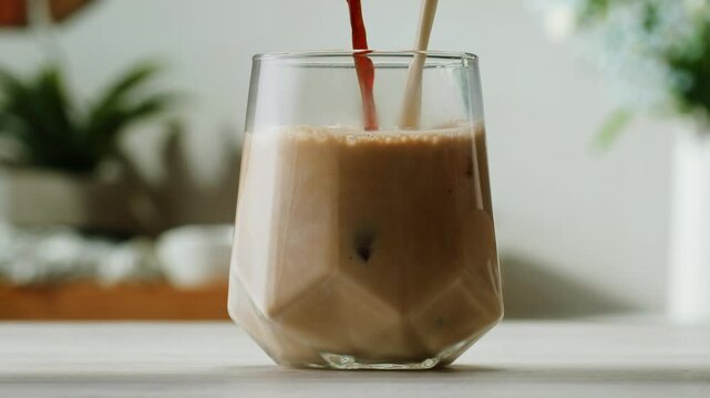Ice coffee latte with cream being poured into it showing the texture and refreshing look of the drink, with a clean background.