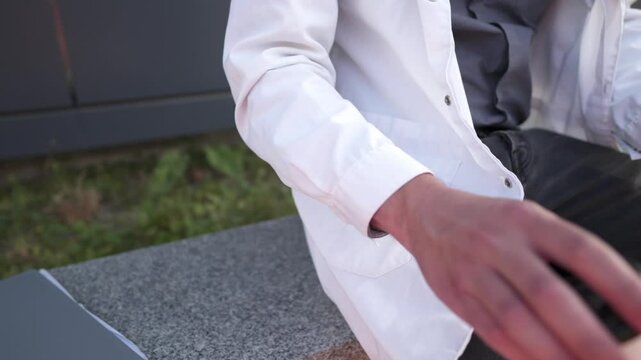 Tired male doctor taking coffee break in backyard of hospital. Exhausted physician throws folder with documents, patient's medical history and takes cup coffee while enjoying hot drink near the clinic