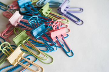 Scattered colorful paper clips on white background, adding playful, organized workspace element