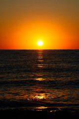 Vibrant Sunset Over Calm Ocean Horizon. A vibrant sunset with a glowing orange sky over a calm ocean horizon, capturing a serene and tranquil seascape.

