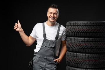 Mechanic showing thumb up with stack of winter tires