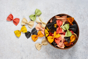 Colorful Italian farfalle pasta in a coconut bowl - top view