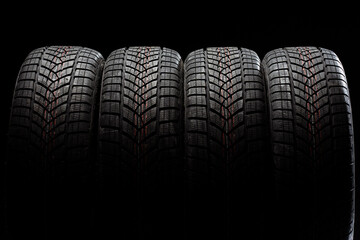 Four winter tires standing on black background © Maria Vitkovska