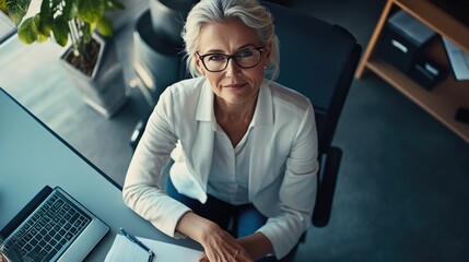A professional woman in corporate attire working at a desk with a computer, focusing on her work.