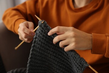 Man knitting with needles at home, closeup