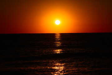 Vibrant Sunset Over Calm Ocean Horizon. A vibrant sunset with a glowing orange sky over a calm ocean horizon, capturing a serene and tranquil seascape.


