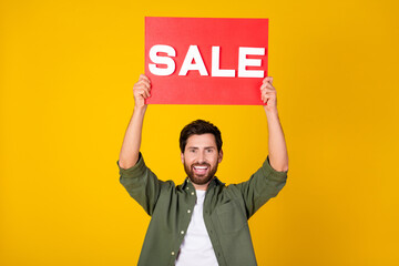 Photo of nice young man hold sale blank wear shirt isolated on yellow color background