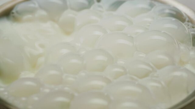 Milk pouring in pot stewpan glass cup close-up. Glass with yogurt, dairy products concept. Drinking fresh lactose-free milk in morning.